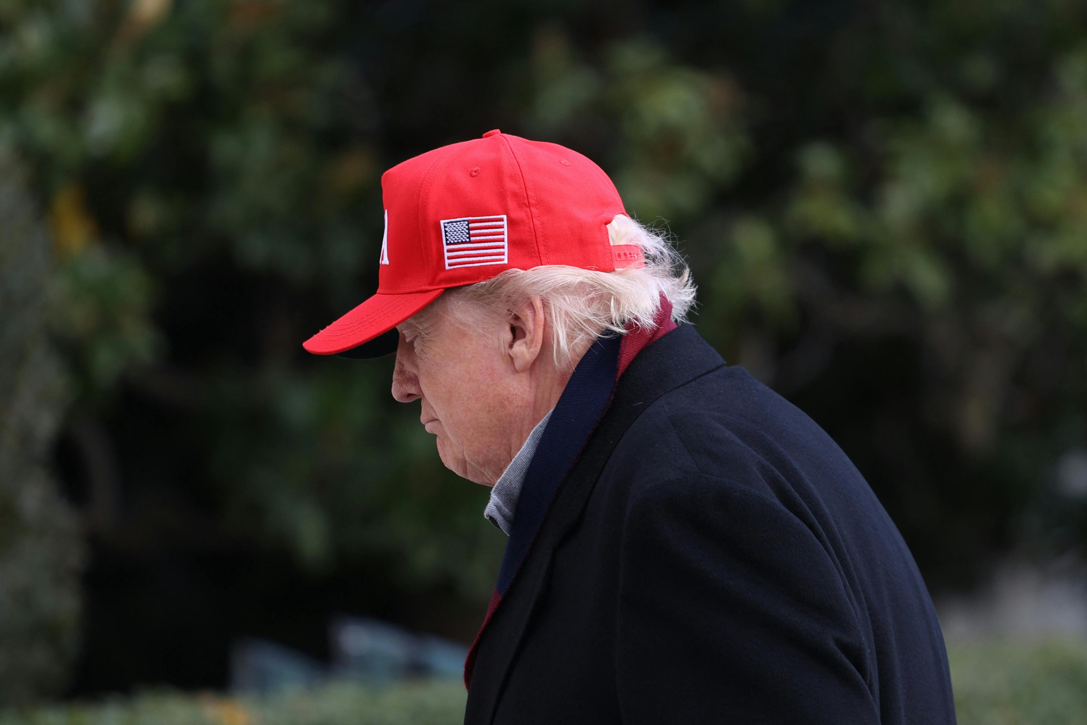 Donald Trump looks down while walking outside the White House