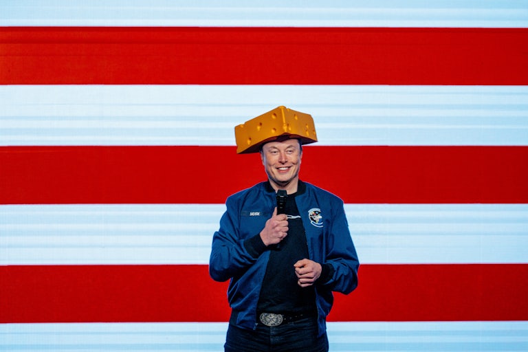 Elon Musk gives a speech in Wisconsin ahead of the Supreme Curt election. He wears a hat that looks like a wedge of cheese and stands in front of a U.S. flag.