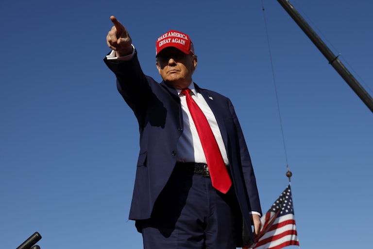 Donald Trump points and wears a MAGA hat