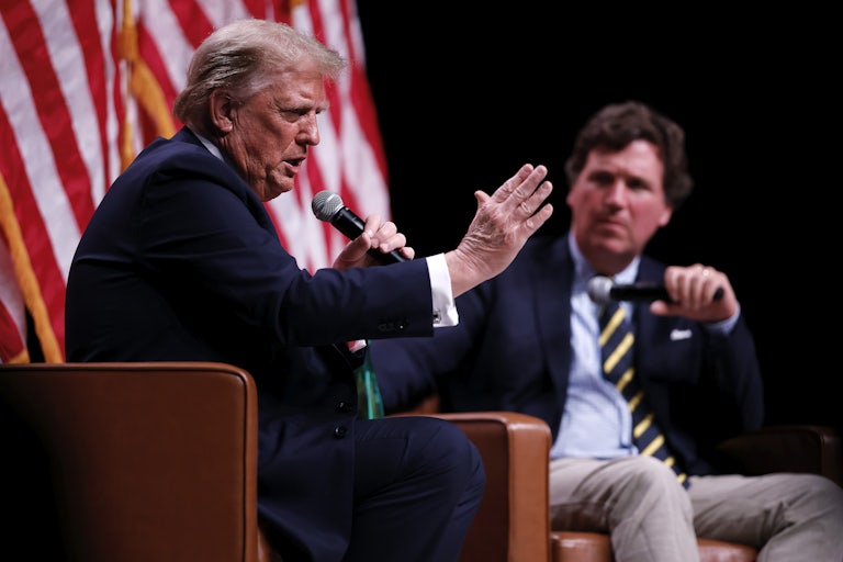Donald Trump gestures while speaking into a hand-held microphone during a conversation with Tucker Carlson