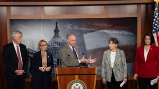 Senator Tim Kaine speaks at a podium about ending the shutdown. He is flanked by Senators Angus King, Maggie Hassan, Jeanne Shaheen, and Catherine Cortez Masto
