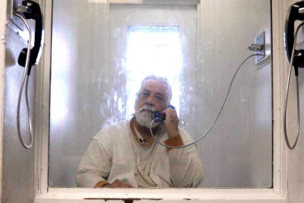 Alvaro Hernandez, better known as Xinachtli, sits behind a layer of glass separating prisoners from visitors in prison.