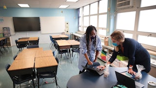 teachers with laptops in an empty Chicago classroom