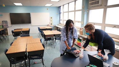 teachers with laptops in an empty Chicago classroom