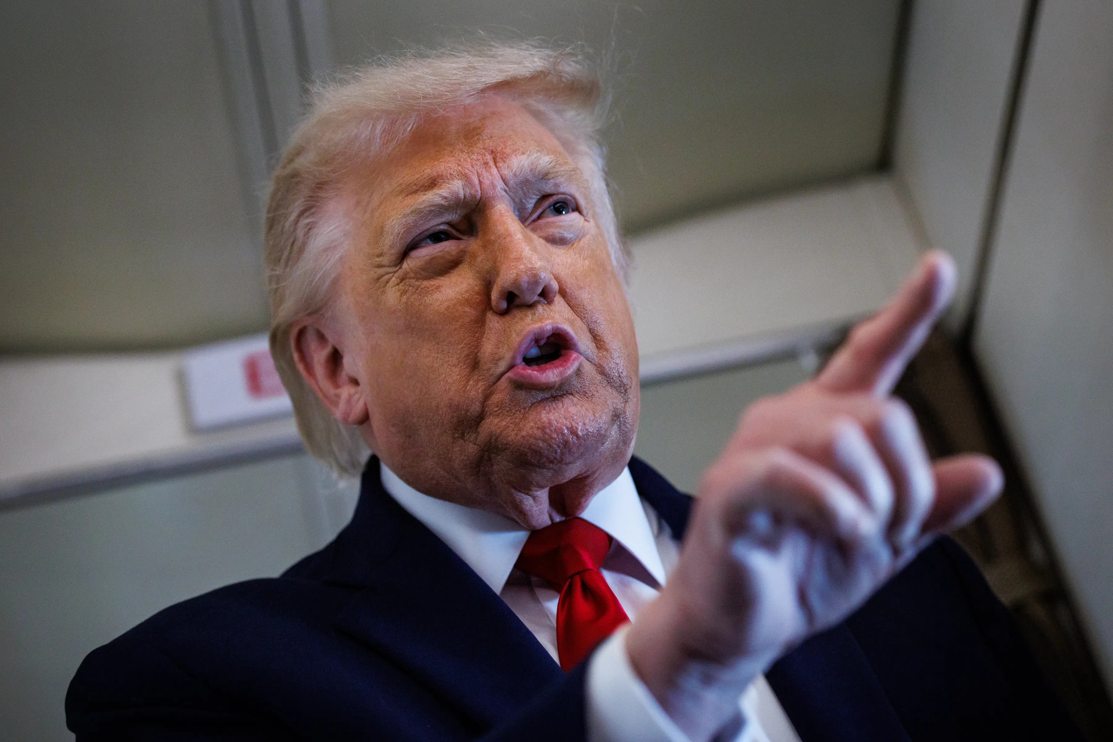 Donald Trump gestures with one finger while speaking to reporters on Air Force One