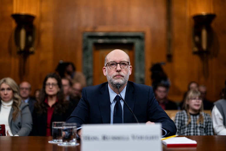 Russell Vought sits at a table during his Senate confirmation hearing