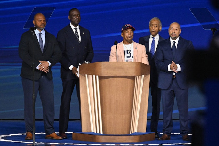 Four members of the Central Park Five and Reverend Al Sharpton stand on stage at the Democratic National Convention