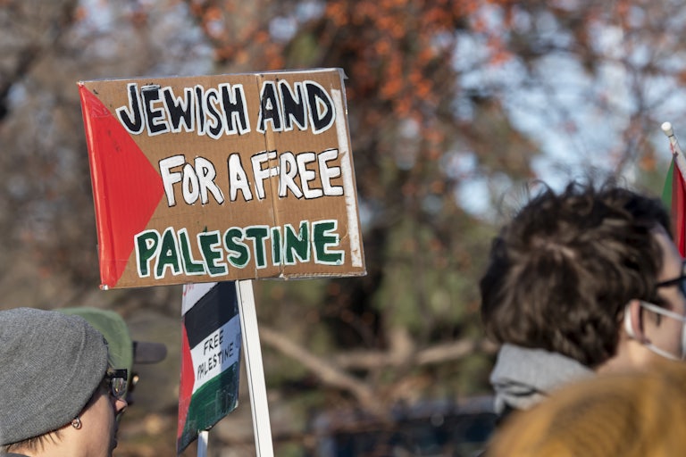 A protester holds a sign that reads "Jewish and for a free Palestine."