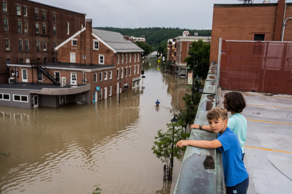 Two children standing on a roof look down at the flooding in Montpeliar, Vermont.