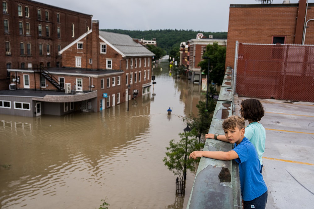 Two children standing on a roof look down at the flooding in Montpeliar, Vermont.