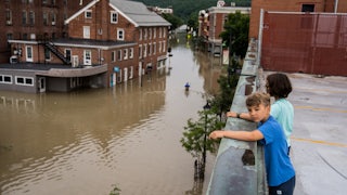 Two children standing on a roof look down at the flooding in Montpeliar, Vermont.