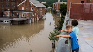 Two children standing on a roof look down at the flooding in Montpeliar, Vermont.