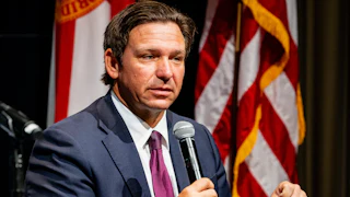 Florida Governor Ron DeSantis speaks into a handheld microphone.