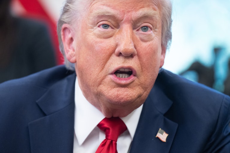Donald Trump speaks to reporters while sitting at his desk in the Oval Office