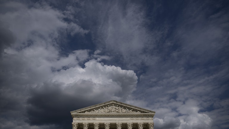 The facade of the Supreme Court appears below darkening skies.