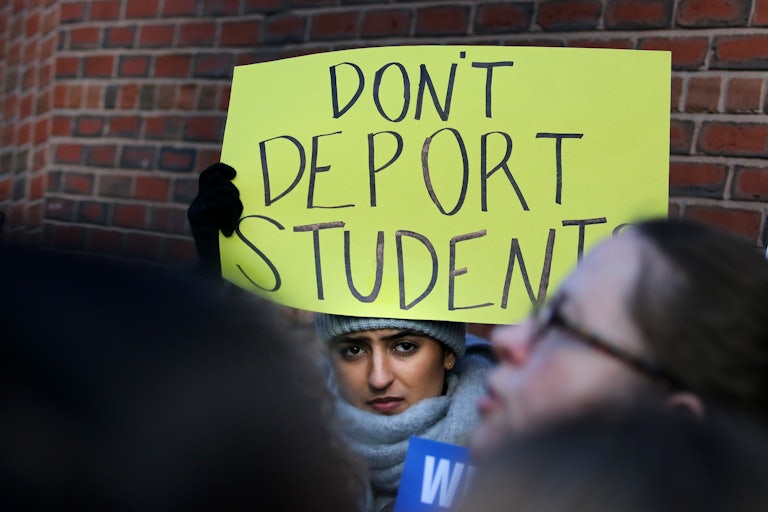 A protester holds a sign reading "Don't Deport Students."