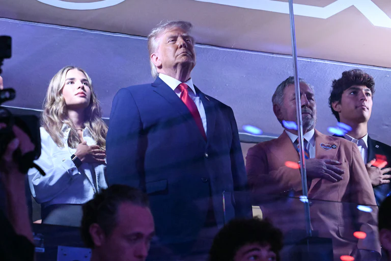 President Donald Trump stands as his granddaughter Kai Trump and Knicks owner James Dolan place their hands over their hearts.