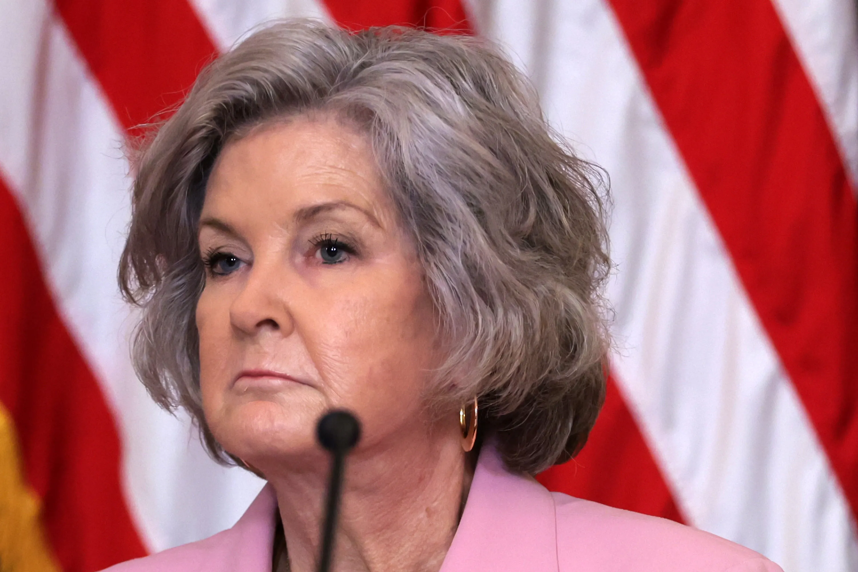 White House Chief of Staff Susie Wiles frowns while sitting in front of a microphone