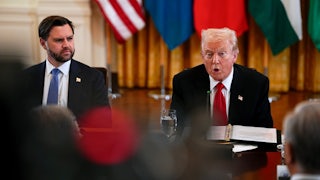 Donald Trump speaks while sitting next to JD Vance at a long table