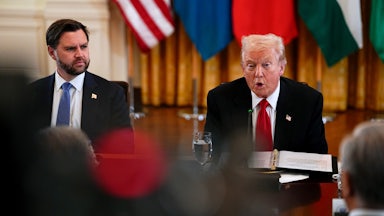 Donald Trump speaks while sitting next to JD Vance at a long table