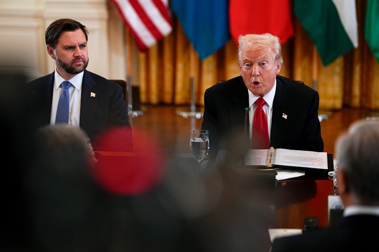 Donald Trump speaks while sitting next to JD Vance at a long table