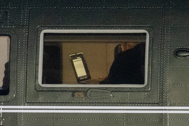 President Donald Trump holds a laptop aboard Marine One