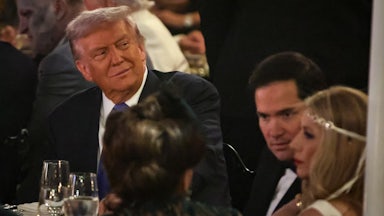Trump sits at a table, wearing a suit, next to Marco Rubio and Jeanette Rubio.