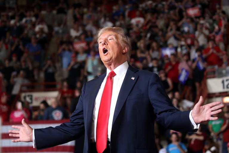 Donald Trump holds his arms out and speaks at a campaign rally