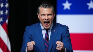 Secretary of Defense Pete Hegseth clenches his fists and screams in front of an American flag