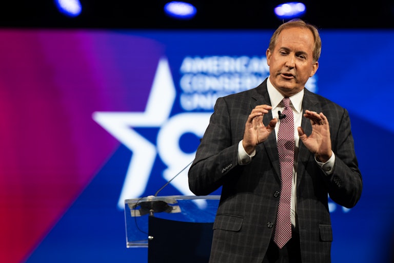 Texas Attorney General Ken Paxton speaks on stage in front of a Conservative Political Action Conference (CPAC) backdrop.