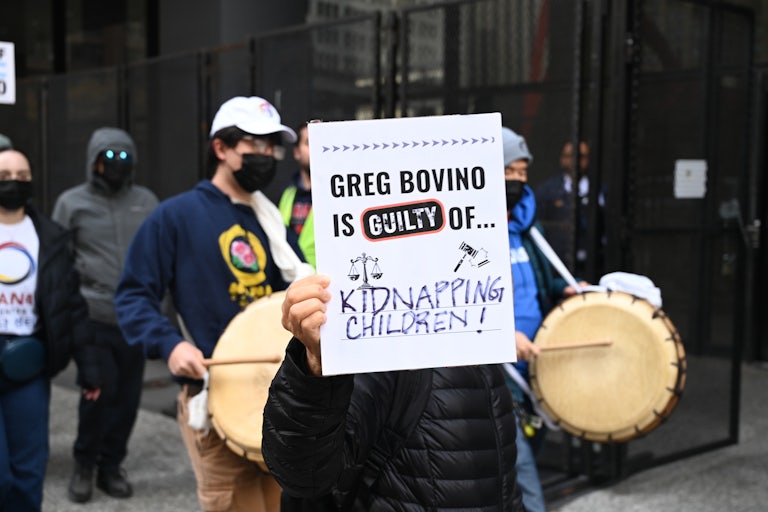 A protester in Chicago holds a sign reading "Greg Bovino Is Guilty Of Kidnapping Children."