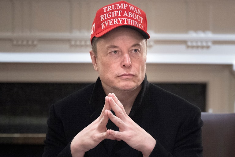 Elon Musk wears a hat that says "Trump was right about everything" and presses his fingertips together while sitting in Donald Trump's Cabinet meeting