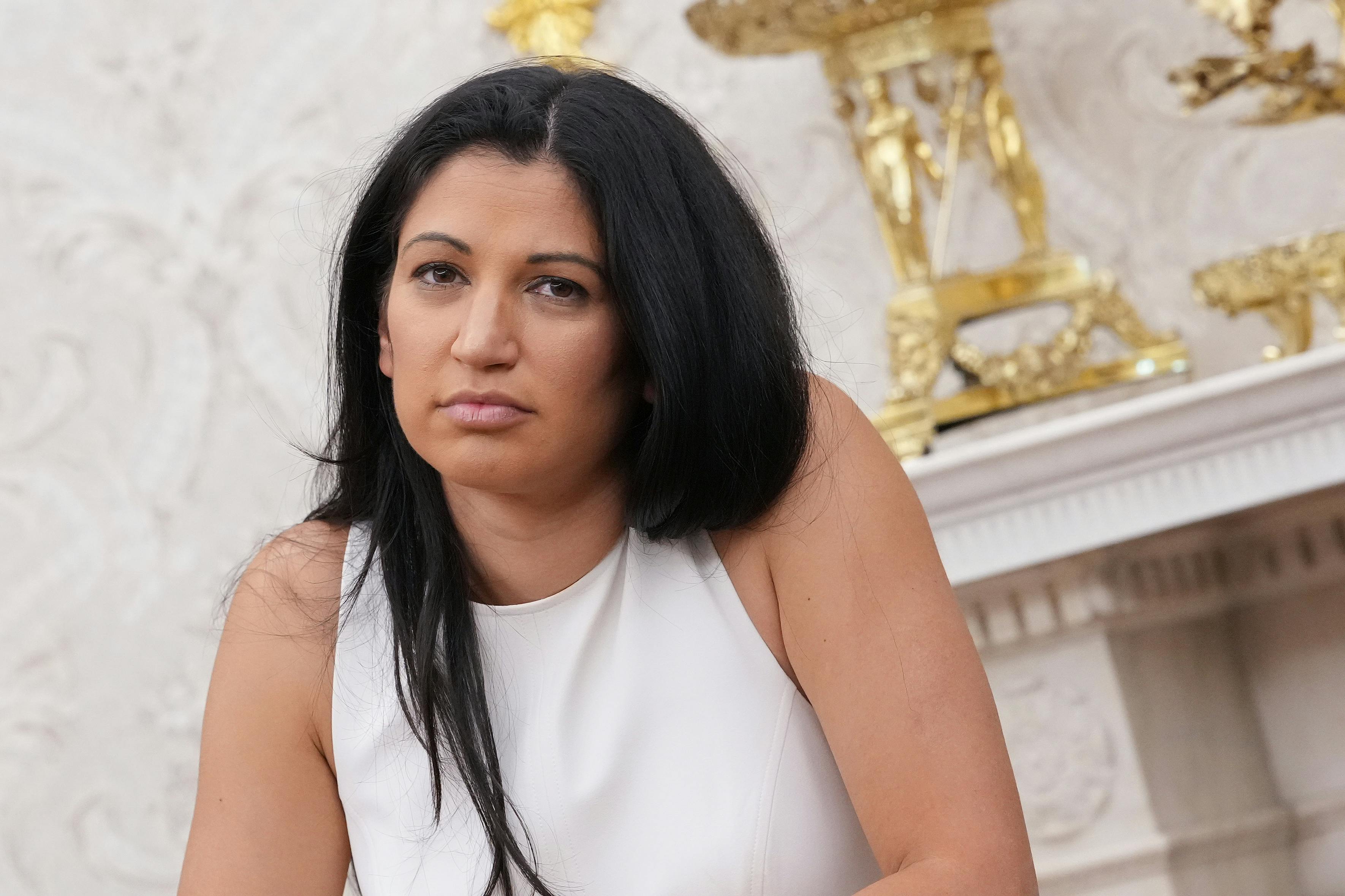 Katie Miller looks unamused while standing in Trump's gold Oval Office.