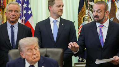 President and Chief Scientific Officer of Regeneron Pharmaceuticals George Yancopoulos speaks alongside Health Secretary Robert F. Kennedy Jr., Director of the Center for Medicare Chris Klomp, and Donald Trump during a White House event on health care affordability in the Oval Office. Trump's eyes are closed.