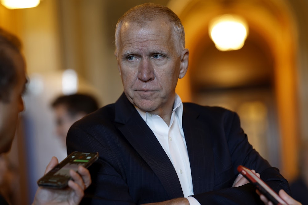 Thom Tillis looks at a reporter holding up a phone.