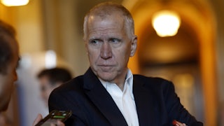 Thom Tillis looks at a reporter holding up a phone.