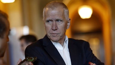 Thom Tillis looks at a reporter holding up a phone.