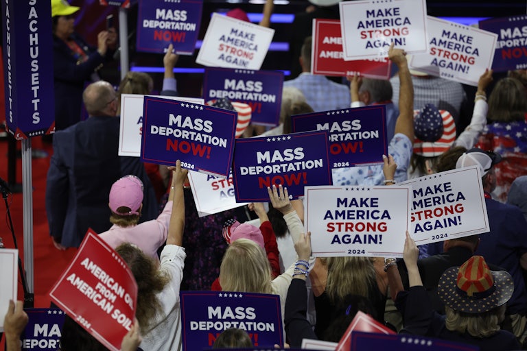 People wave signs that say “Mass Deportation Now” at the Republican National Convention
