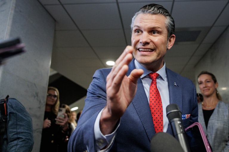 Pete Hegseth gestures while speaking to reporters