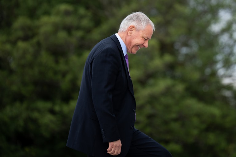 Ken Buck is seen in profile smiling and walking