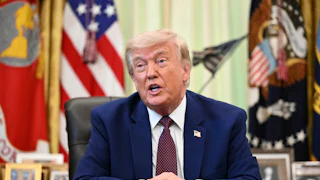 Donald Trump speaks while seated at his desk in the Oval Office of the White House