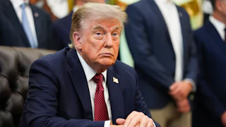 Donald Trump sits at his desk in the Oval Office.
