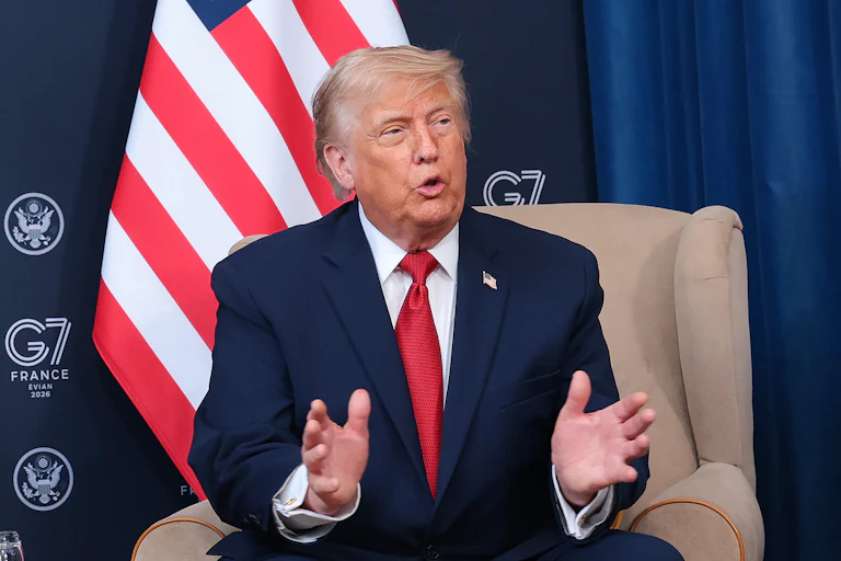 Donald Trump gestures and speaks while sitting in a press conference at the G7 summit
