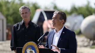 California Governor Gavin Newsom listens as state Attorney General Rob Bonta speaks at a podium with the state seal.