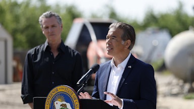 California Governor Gavin Newsom listens as state Attorney General Rob Bonta speaks at a podium with the state seal.