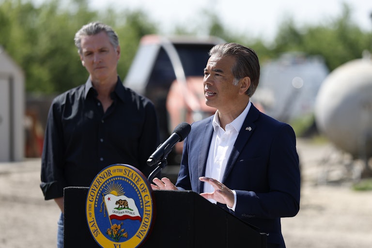 California Governor Gavin Newsom listens as state Attorney General Rob Bonta speaks at a podium with the state seal.