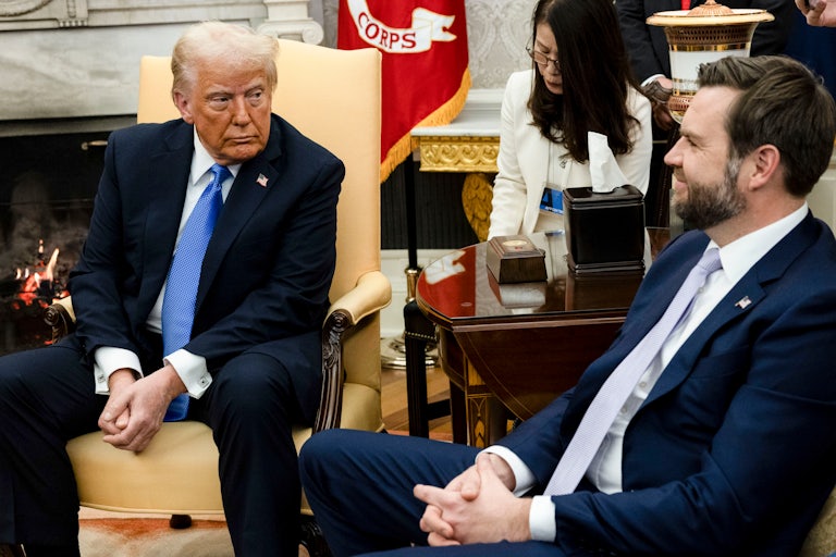 Donald Trump looks at JD Vance, who smiles back at him as they sit in the Oval Office
