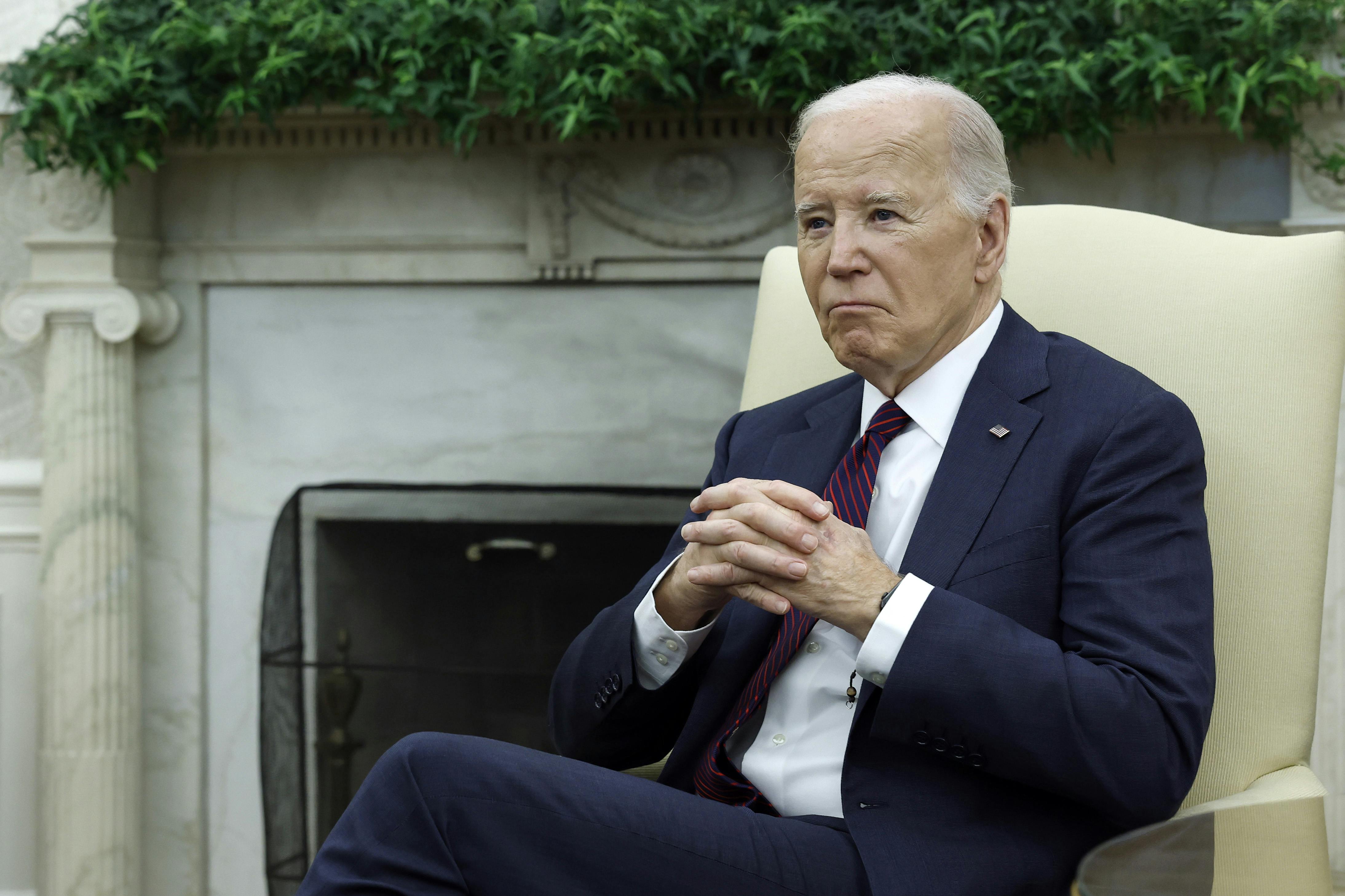 Joe Biden folds his hands while sitting in the Oval Office. 