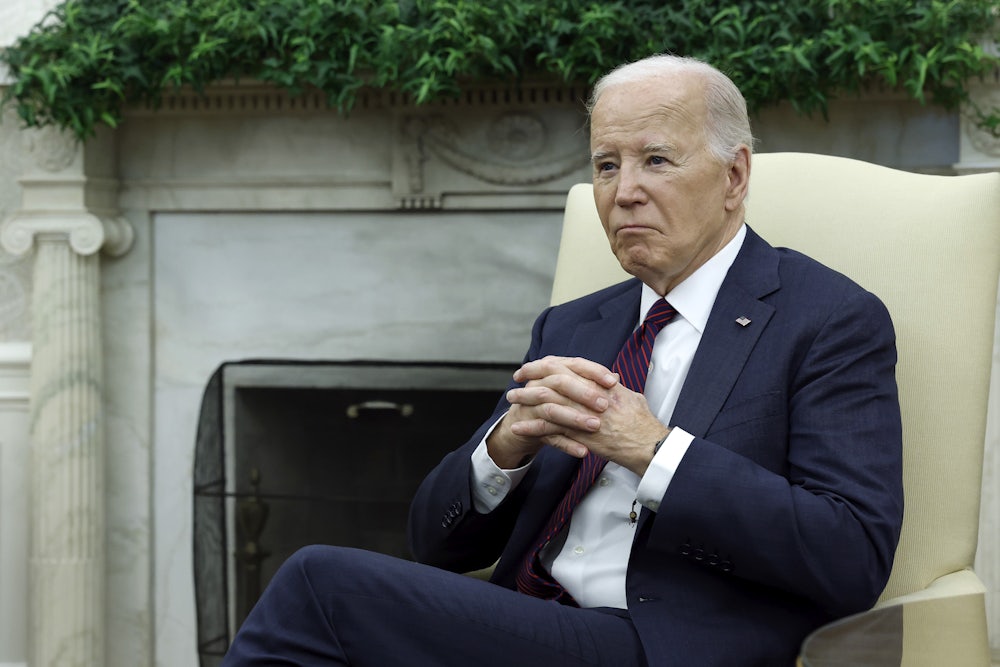 Joe Biden folds his hands while sitting in the Oval Office.
