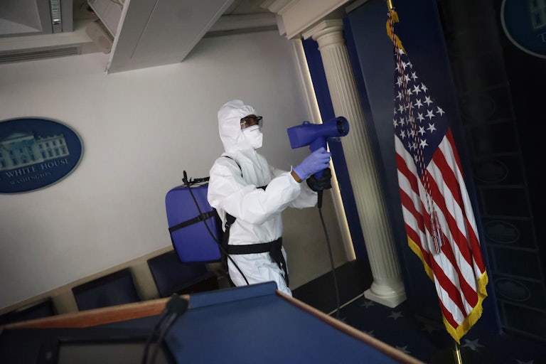 A member of the White House cleaning staff sanitizes the James S. Brady Press Briefing Room as a precaution after President Donald Trump, several members of his staff, and three members of the press corps tested positive for coronavirus.